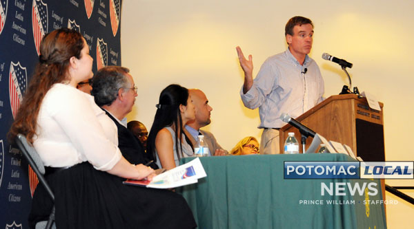 Senator Mark Warner (behind podium) calls for local leaders and those in the business community to get behind national immigration reform. [Mary Davidson / Potomac Local News]