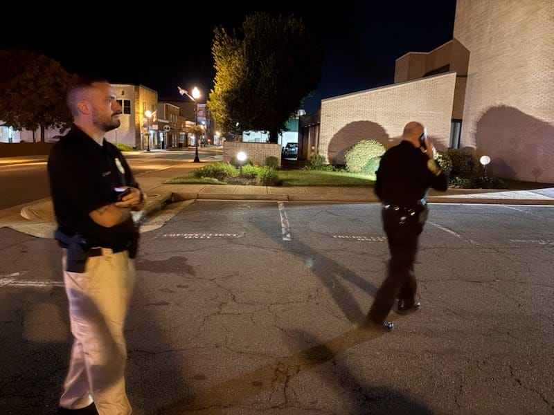 Manassas Police Chief Doug Keen talks on the phone beside a detective.