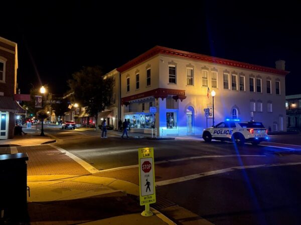 Manassas police cruiser at an Old Town intersection at night.