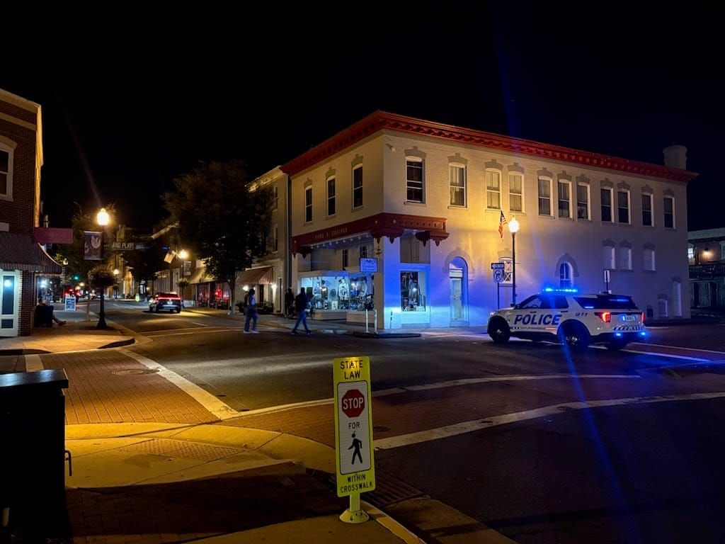 Manassas police cruiser at an Old Town intersection at night.
