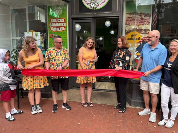 Rita Linnell-Witte holds ceremonial scissors at the Always Flavored sixth-anniversary ribbon cutting at 619 Caroline Street in Fredericksburg.