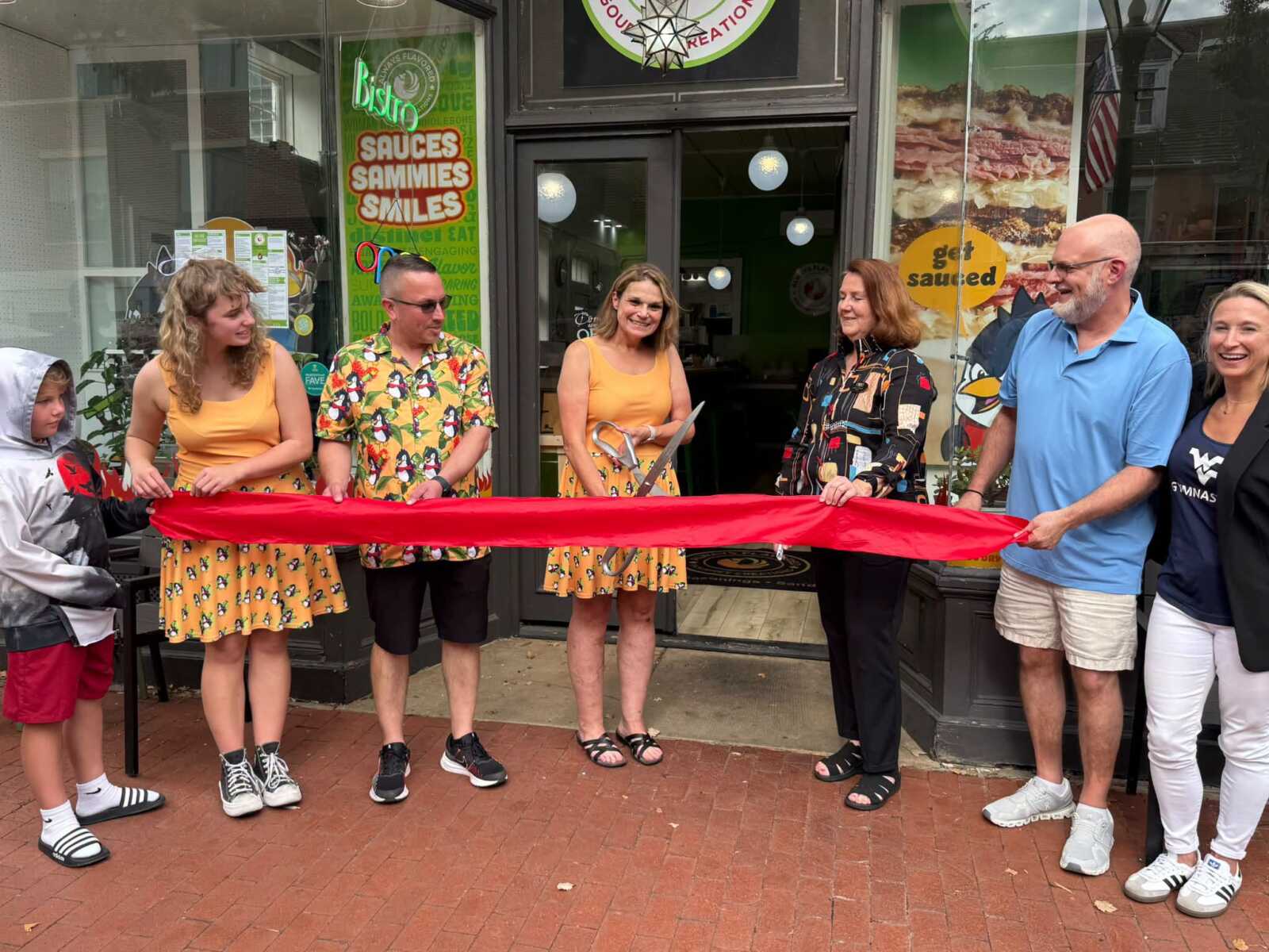 Rita Linnell-Witte holds ceremonial scissors at the Always Flavored sixth-anniversary ribbon cutting at 619 Caroline Street in Fredericksburg.