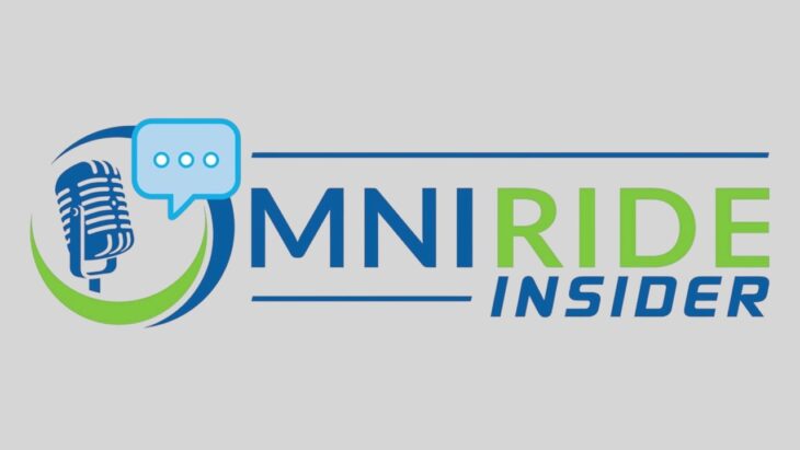 Alyson Foster and Byren Lloyd sit at a table under an OmniRide Insider sign with an OmniRide bus behind them.