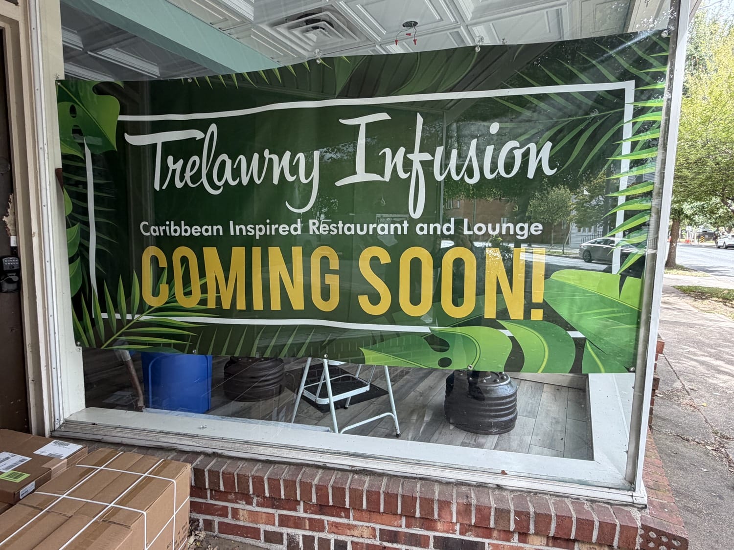 A Coming Soon banner for Trelawny Infusion in the window at 1108–1110 Caroline Street in downtown Fredericksburg